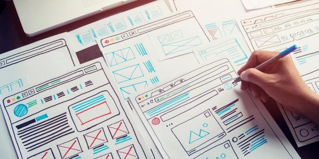 persona escribiendo sobre planos de Diseño UX UI sobre papel